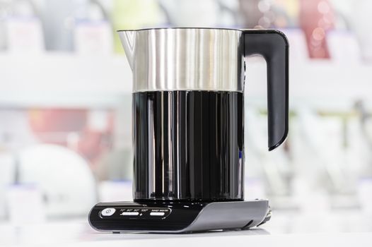 Single brand new premium electric kettle at retail store shelf, defocused background