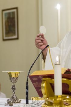 Priest celebrating the communion with goblet and holy bread