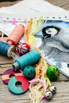 Set of threads for embroidery on background of handmade paintings