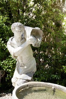 Ancient sculpture of a man with a bucket of water in Boboli Gardens ,Florence, Italy.