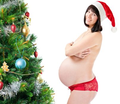 Pregnant young woman near decorated christmas tree isolated on white