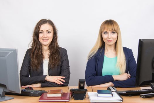 Two young pretty business woman sitting at a office table is divided into two jobs