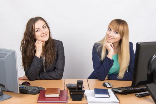 Two young pretty business woman sitting at a office table is divided into two jobs