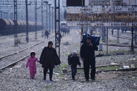 GREECE, Idomeni: Refugees walk near railway tracks near the Greek village of Idomeni, on March 2, 2016. The migrants are waiting for the Macedonian authorities to open the border so they can continue their journey through Europe.