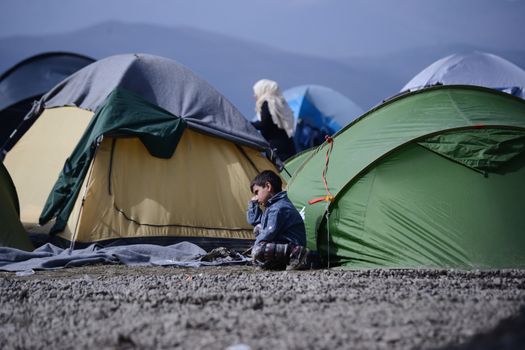 GREECE, Idomeni: A young boy sits outside a tent near the Greek village of Idomeni, on March 2, 2016. The migrants are waiting for the Macedonian authorities to open the border so they can continue their journey through Europe.