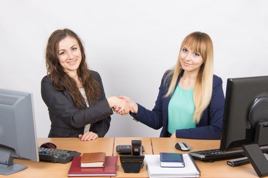 Two young pretty business woman sitting at a office table is divided into two jobs