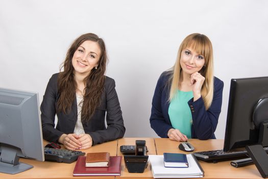 Two young pretty business woman sitting at a office table is divided into two jobs