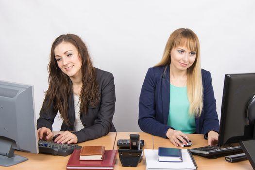 Two young pretty business woman sitting at a office table is divided into two jobs