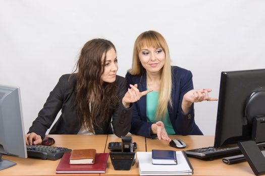 Two young pretty business woman sitting at a office table is divided into two jobs