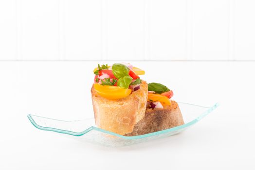 Colorful bruschetta on a glass plate.  Suitable for many food service promotional materials.