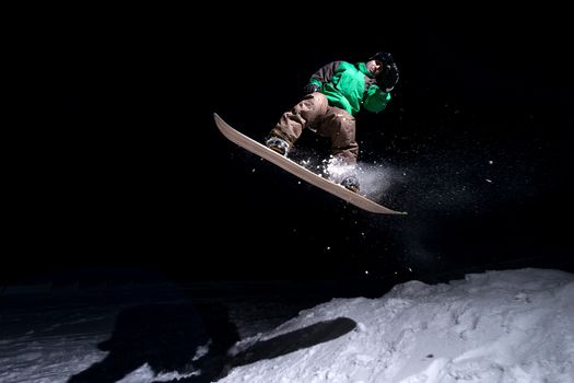 Snowboarder jumping at night