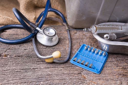 Old medical syringes , hypodermic needles and stethoscope on old wood background