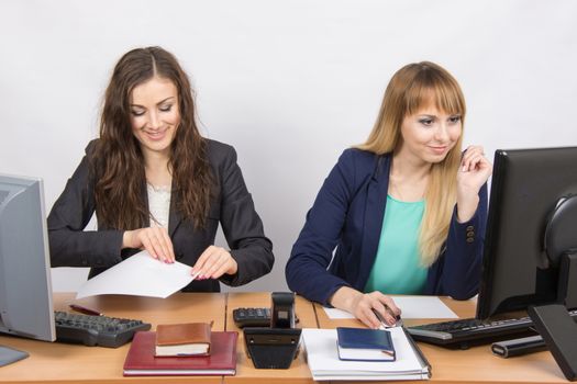 Two young pretty business woman sitting at a office table is divided into two jobs