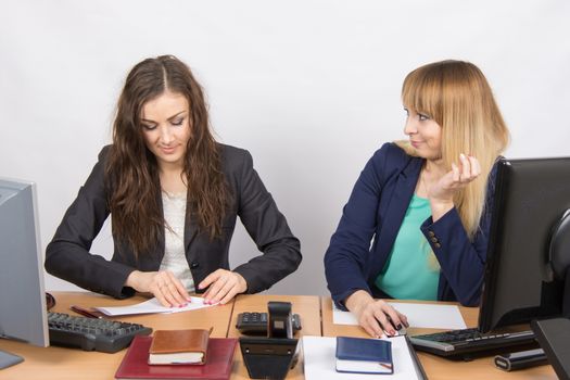 Two young pretty business woman sitting at a office table is divided into two jobs