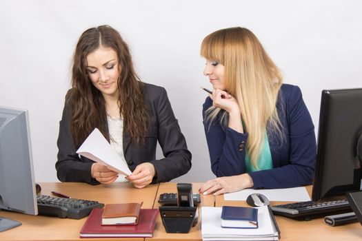 Two young pretty business woman sitting at a office table is divided into two jobs