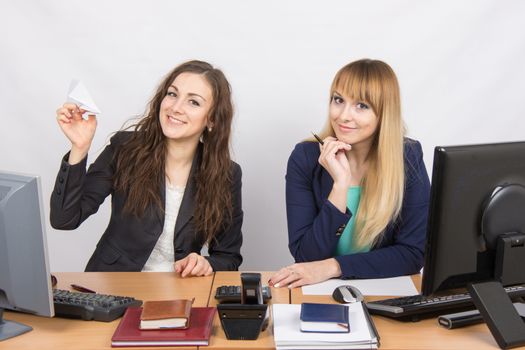 Two young pretty business woman sitting at a office table is divided into two jobs