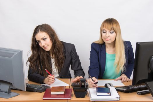 Two young pretty business woman sitting at a office table is divided into two jobs