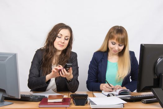 Two young pretty business woman sitting at a office table is divided into two jobs