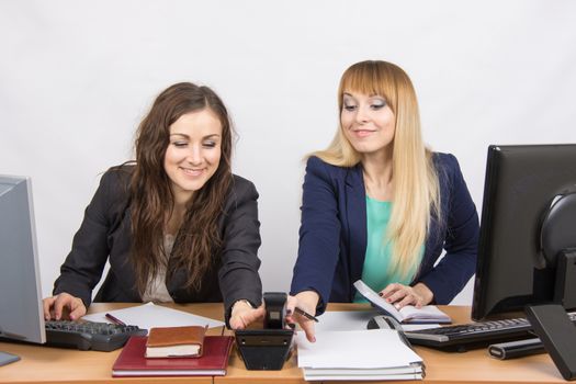 Two young pretty business woman sitting at a office table is divided into two jobs