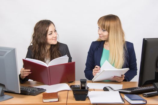 Two young pretty business woman sitting at a office table is divided into two jobs