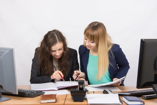 Two young pretty business woman sitting at a office table is divided into two jobs