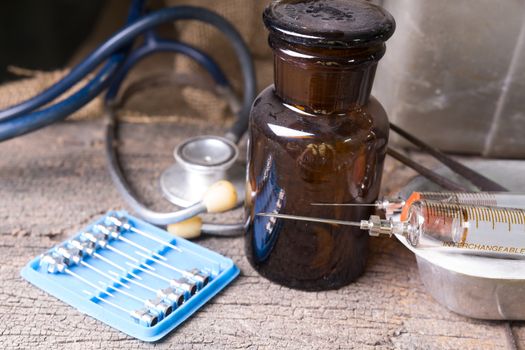 Old medical syringes , hypodermic needles and stethoscope on old wood background