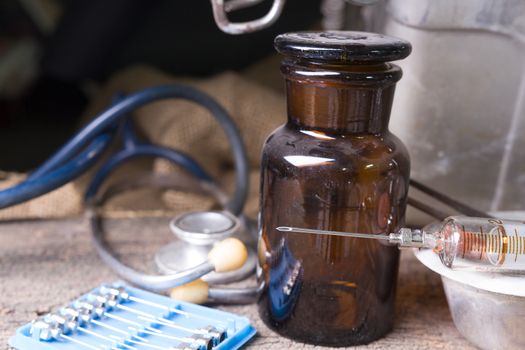 Old medical syringes , hypodermic needles and stethoscope on old wood background