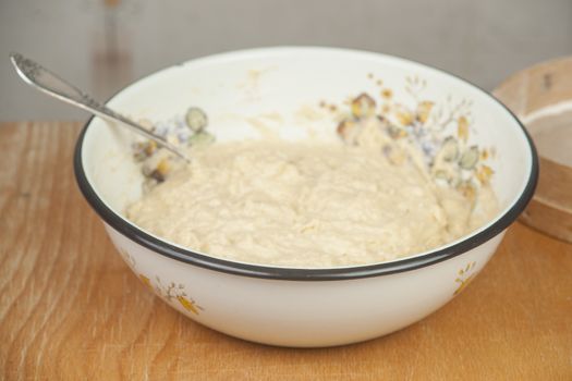 Fresh yeast dough in the dish on the wooden table