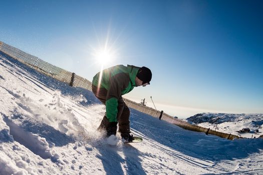 Snowboard freerider in the mountains against sun shine in blue sky.