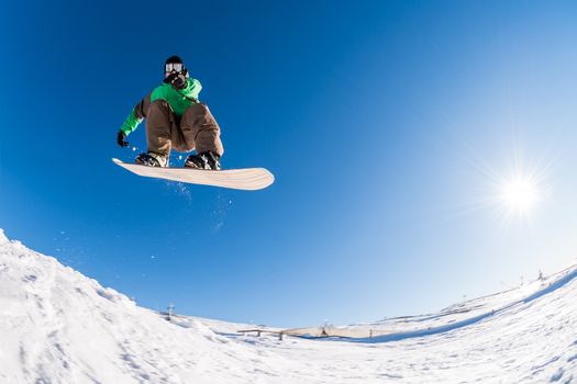 Snowboarder executing a radical jump against blue sky.