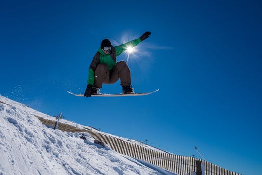 Snowboarder executing a radical jump against blue sky.