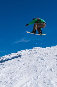 Snowboarder executing a radical jump against blue sky.