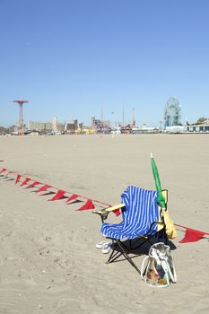 empty chair with towel on sunny coney island beach waits for sitter  to return