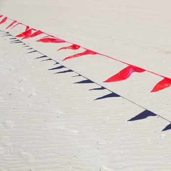 small red flags in wind against sand of beach