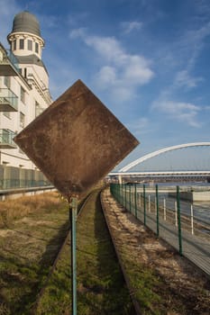 The end of one of the railways line. Back side of the traffic sign. Building and an Apollo bridge in the background. Blue sky with contrast white clouds.