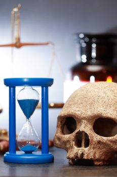 Medical laboratory. Human skull near hourglass on background with weight scale and flasks