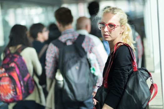 Young blond caucsian woman waiting in queue to board a plane.