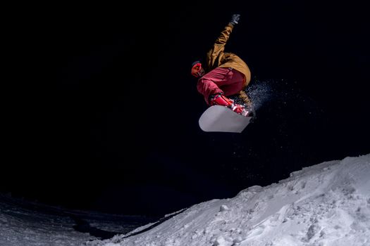 Snowboarder jumping at night.