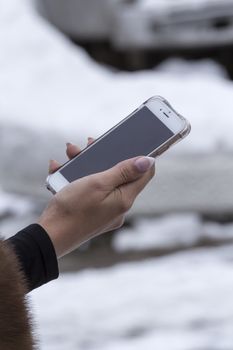 mobile phone in a female hand on a white premise