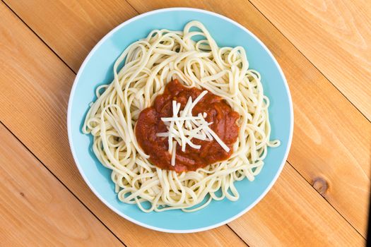 Simple plate of Italian spaghetti Bolognese or Bolognaise topped with a tomato sauce and grated gruyere cheese, overhead view