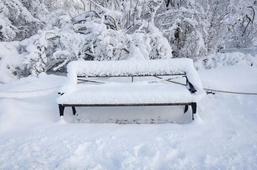 one bench with snow on in the winter not so easy to take a rest
