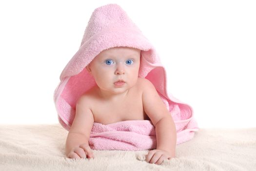 Adorable baby girl, looking out under a pink towel