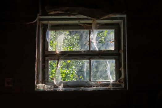 Old window on the soil of the old house with the net