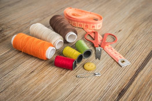 Sewing background. Accessories for needlework on wooden background. Spools of thread, scissors, buttons, measuring tape, sewing supplies. Set for needlework top view with copy space.