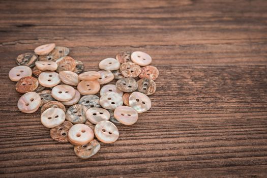 Valentine heart buttons textilesover rustic wooden texture. Top view with copy space.
