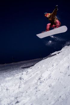 Snowboarder jumping at night.