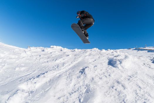 Snowboarder executing a radical jump against blue sky.