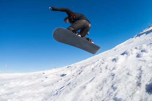 Snowboarder executing a radical jump against blue sky.