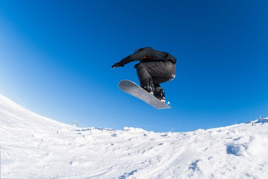 Snowboarder executing a radical jump against blue sky.