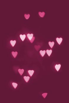 Dark purple background of pink heart shapes that appear to float at random